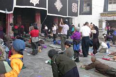 
We watched the devout pilgrims prostrate themselves at the Jokhang Temple’s entrance doors. Their hands are protected by large mittens or small block of wood fixed to the waist by a lace. People kneel, their hands reach the ground and they start sliding until the whole body extends on the ground too. Standing up they then repeat the action again and again.
